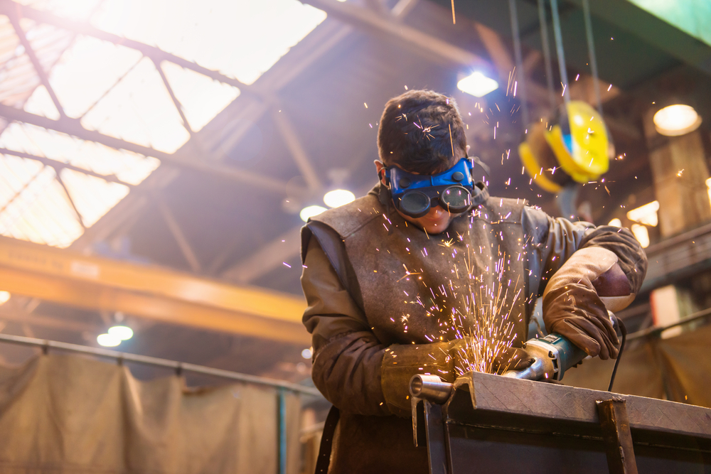 Young,Man,With,Protective,Goggles,Welding,In,A,Factory
